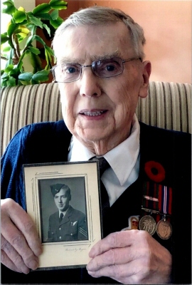 Don Brewster holding photo of himself in uniform