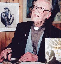 Father Anselme Chiasson with pen at desk